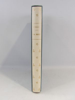 un vieux livre posé sur une table à côté d'un mur blanc