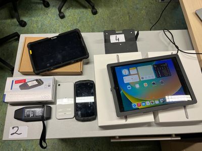 une tablette posée sur une table, à côté d'autres appareils électroniques