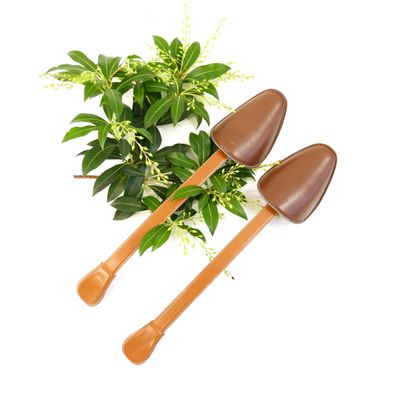 two shovels sitting next to a potted plant on a white surface