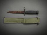 a knife that is laying next to a green strap