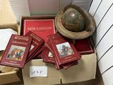 Des cartons remplis de livres et un globe terrestre sont posés par terre devant un mur