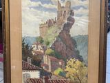 painting of a castle on a hill in a frame on a table