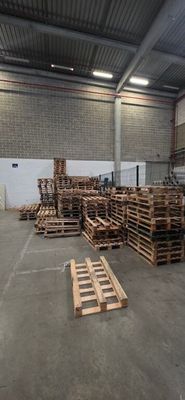 a large warehouse with pallets of wood in the middle of the floor