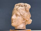 statue of a woman ' s head on a wooden stand against a gray background