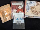 Plusieurs livres sont posés sur une surface noire, sur fond noir.