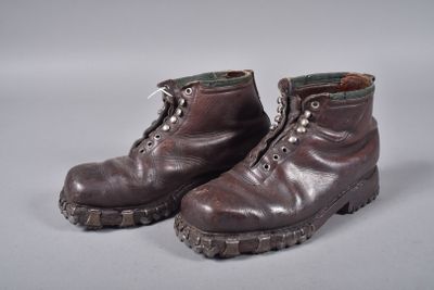 une paire de bottes en cuir marron à lacets posées sur une surface grise
