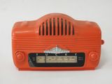 une radio orange posée sur une table près d'un mur blanc