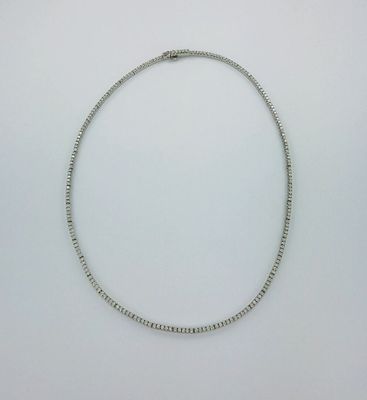 gros plan d'un collier en argent sur une surface blanche