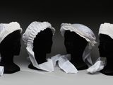 trois têtes de mannequins noires ornées de volants blancs et un rouleau de papier toilette