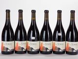 six bottles of wine are lined up in a row on a white surface