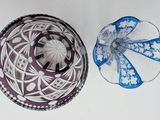 a purple and white bowl and a blue and white bowl on a white surface