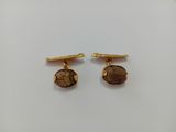a pair of gold tone cufflinks with a brown stone