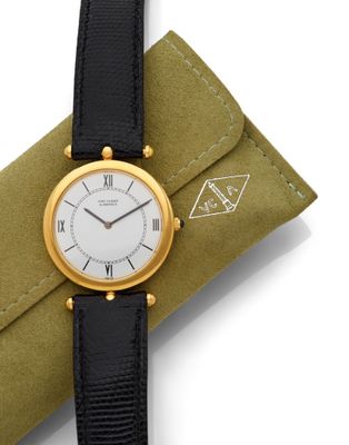 an image of a gold and black watch on a green case