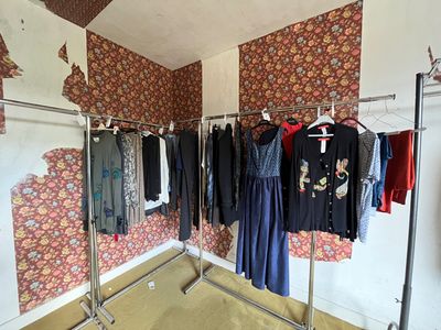 a photo of a clothes rack in a room with a wallpapered wall