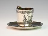 a silver cup and saucer sitting on a saucer