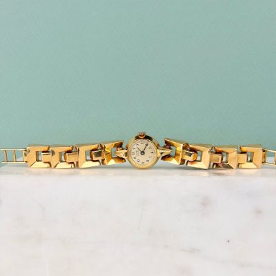une photo d'une montre en or posée sur un comptoir en marbre