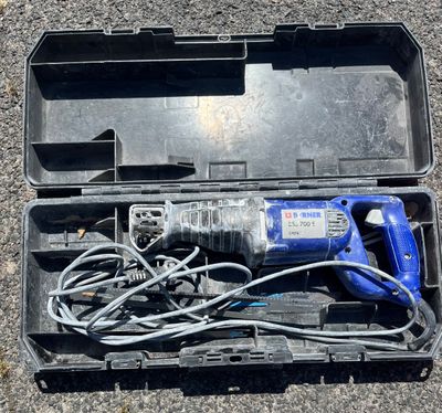 a blue electric drill in a black case on the ground