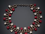 a necklace with red and white stones on a black background