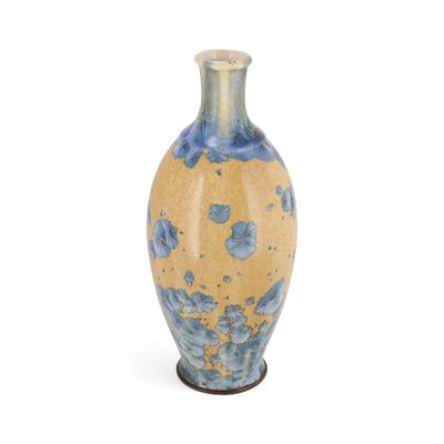un vase bleu et jaune posé sur une surface blanche