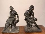 une paire de statues en bronze représentant un homme et une femme assis sur un rocher