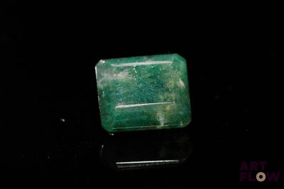 un gros plan d'une émeraude verte sur une surface noire