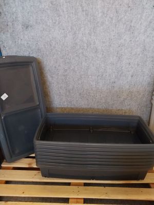 un conteneur en plastique posé sur une palette à côté d'un autre conteneur en plastique