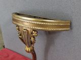 une console en laiton surmontée d'un miroir, posée sur une nappe rouge