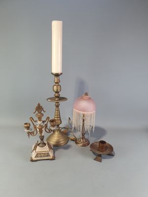 une bougie, un bougeoir, une lampe et d'autres objets posés sur une table
