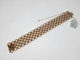 a close up of a gold bracelet on a white surface
