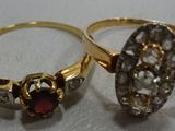 two gold rings with garnets on them sitting on a table