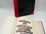 un livre ouvert posé sur une table blanche, à côté d'un livre rouge et noir