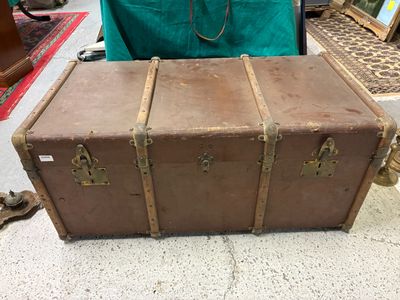 une valise marron posée par terre à côté d'une chaise verte