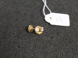 a pair of gold and diamond earrings on a black surface
