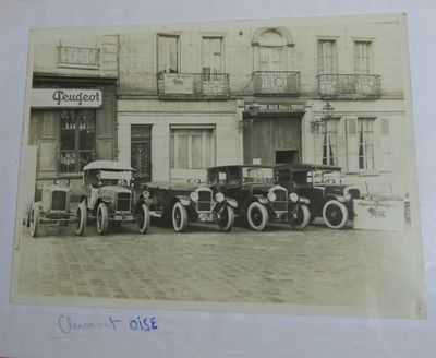 une photo montrant un groupe de voitures anciennes garées devant un immeuble