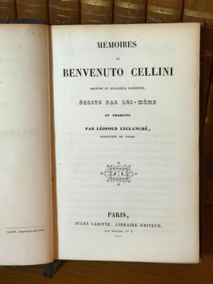 un livre ouvert posé sur une table en bois, à côté d'une pile de livres