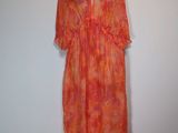 an orange dress on a mannequin stand against a white wall