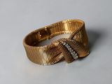 a close up of a gold bracelet with a bow on it