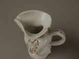 a small white vase with a gold decoration on it