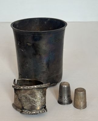 une tasse en argent et un dé à coudre posés sur une table