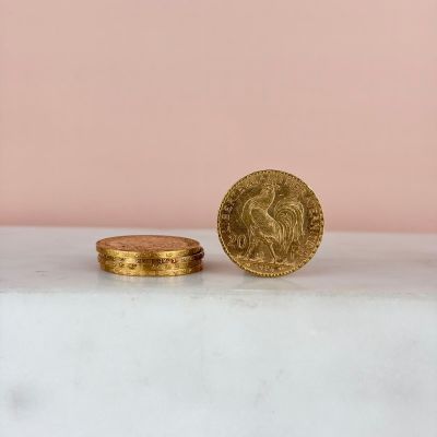 une pièce d'or posée sur un comptoir blanc, près d'un mur rose