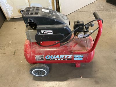 a small air compressor sitting on the floor in the garage