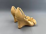 une image représentant une paire de chaussures dorées posées sur une surface grise
