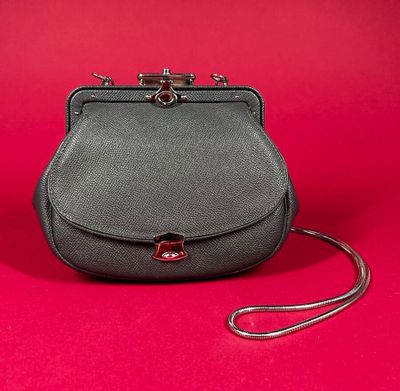 a black leather purse with a metal handle on a red background
