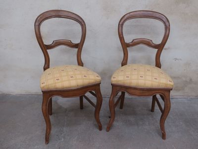 two wooden chairs with plaid upholstered seats in front of a wall