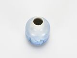 a small blue and white vase on a white surface