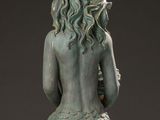 statue of a mermaid sitting on a rock with her back to the camera