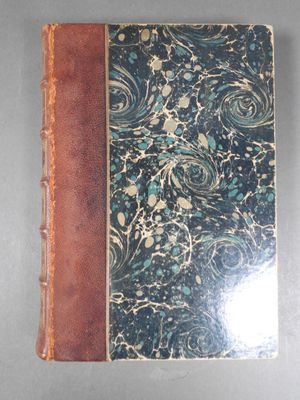 an old book sitting on top of a table covered in blue and brown paper