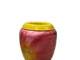 un vase rouge avec un couvercle jaune posé sur une surface blanche