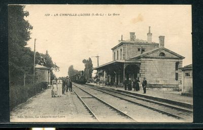 une photo en noir et blanc d'une gare où l'on voit des gens debout sur les voies