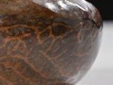 a brown vase sitting on a table with a black background